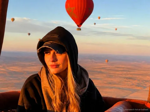 Aufsteigender Heißluftballon bei Sonnenaufgang über der Landschaft von Marrakesch